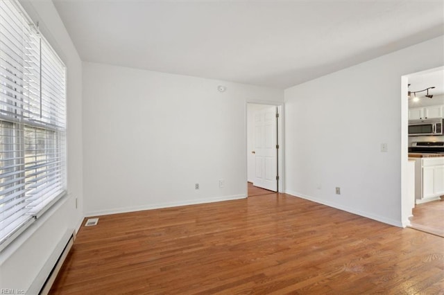 spare room featuring hardwood / wood-style flooring and a baseboard heating unit