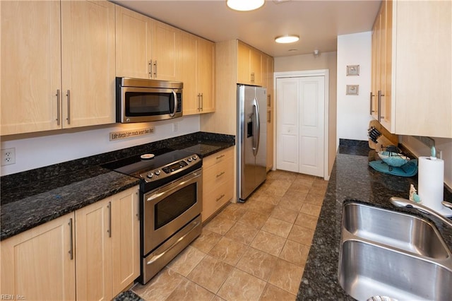 kitchen featuring dark stone countertops, stainless steel appliances, light brown cabinets, and sink