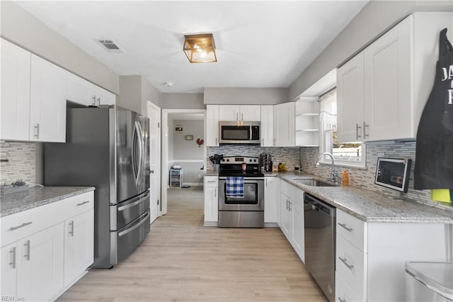 kitchen with stainless steel appliances, white cabinetry, sink, and light wood-type flooring