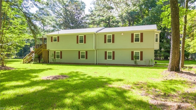 back of property featuring a sunroom and a lawn