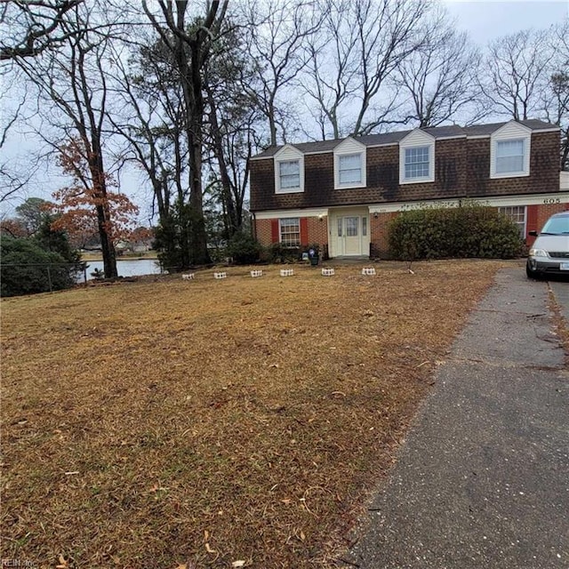 view of front of home featuring brick siding, a water view, a gambrel roof, and roof with shingles