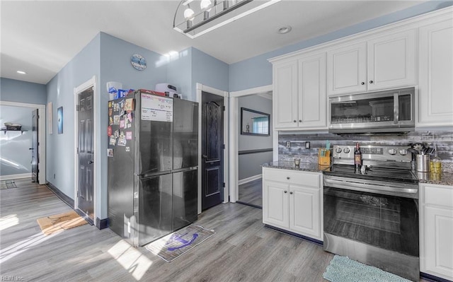 kitchen with stainless steel appliances, white cabinets, and dark stone counters