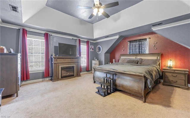 bedroom featuring ceiling fan, lofted ceiling, a tray ceiling, and carpet floors