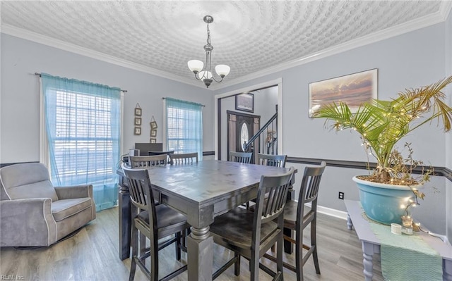 dining space with ornamental molding, hardwood / wood-style floors, and a notable chandelier