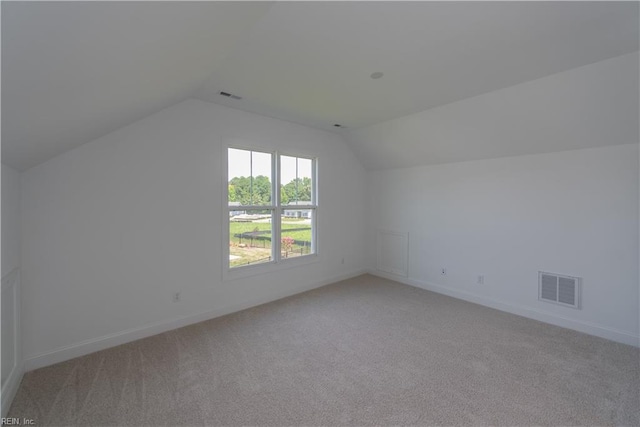 bonus room with vaulted ceiling and light carpet