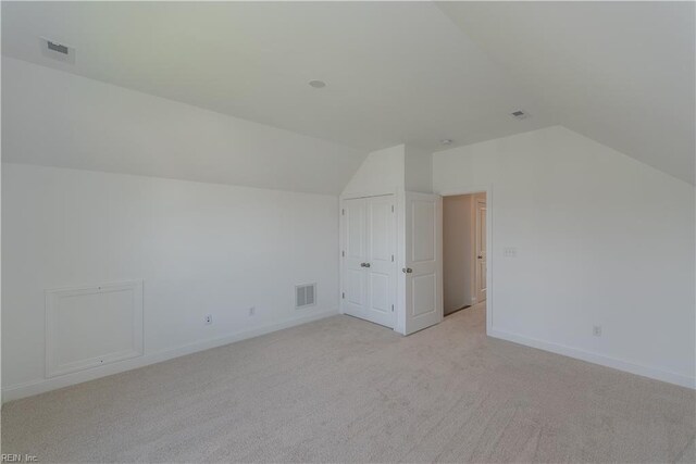 bonus room with vaulted ceiling and light colored carpet