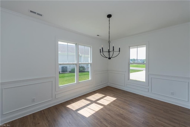unfurnished dining area featuring a notable chandelier, ornamental molding, and dark hardwood / wood-style floors