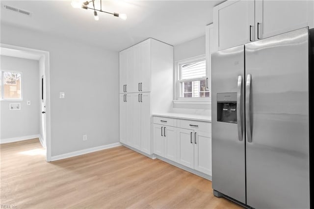 kitchen with stainless steel refrigerator with ice dispenser, white cabinets, and light wood-type flooring