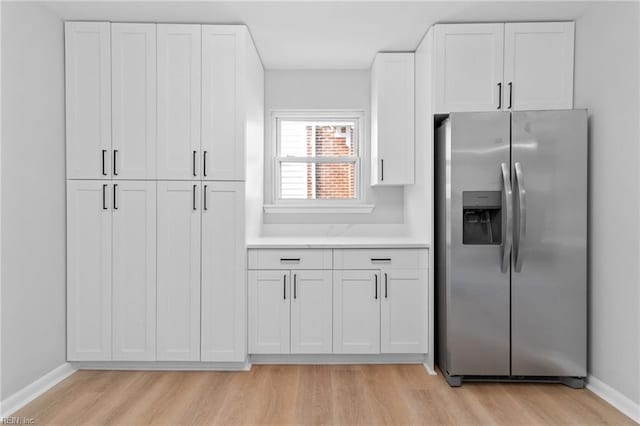 kitchen featuring stainless steel refrigerator with ice dispenser, white cabinets, and light wood-type flooring