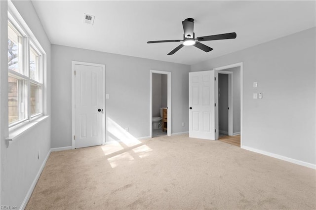 unfurnished bedroom featuring light carpet, ensuite bath, and ceiling fan