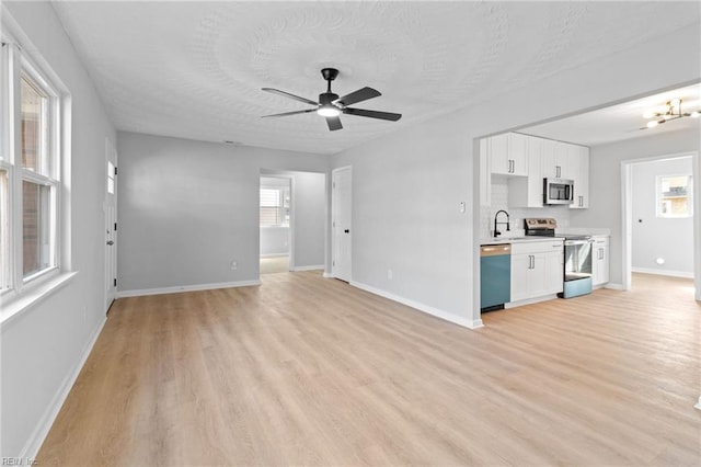 unfurnished living room with ceiling fan, sink, a textured ceiling, and light wood-type flooring