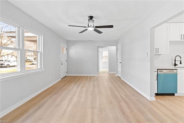 unfurnished living room with ceiling fan, sink, a textured ceiling, and light hardwood / wood-style floors