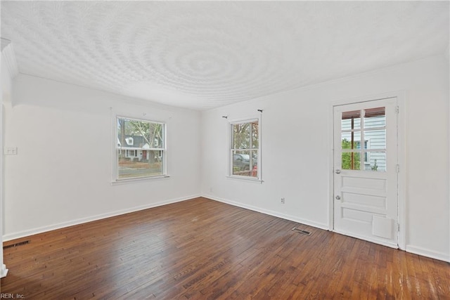 spare room with dark hardwood / wood-style flooring and plenty of natural light