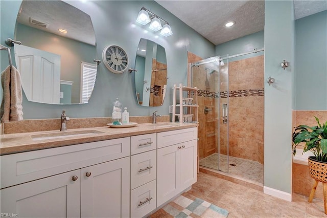 bathroom with vanity, tile patterned floors, a textured ceiling, and a shower with shower door