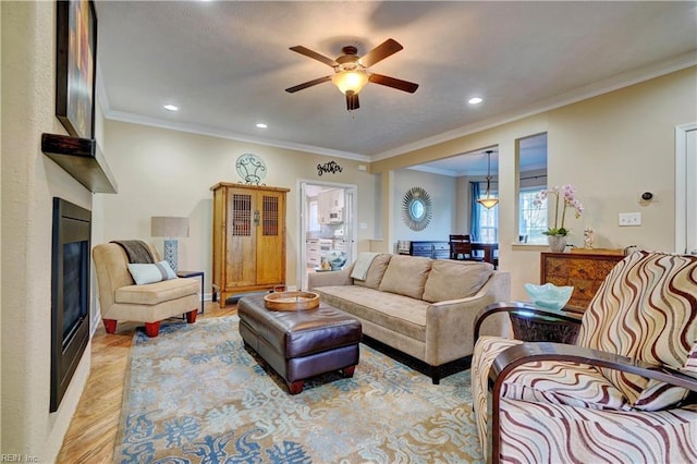 living room featuring ceiling fan, ornamental molding, and light hardwood / wood-style floors