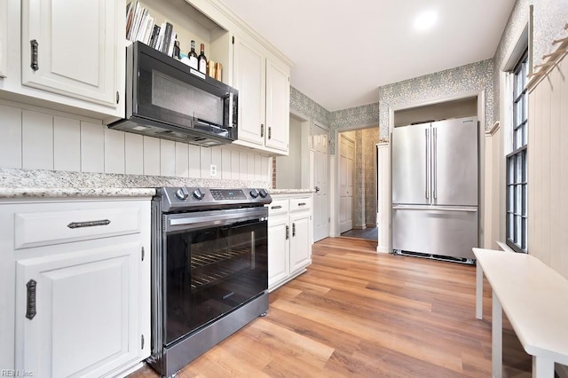 kitchen with white cabinetry, appliances with stainless steel finishes, and light hardwood / wood-style floors