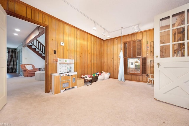 miscellaneous room with wooden walls, carpet flooring, and track lighting