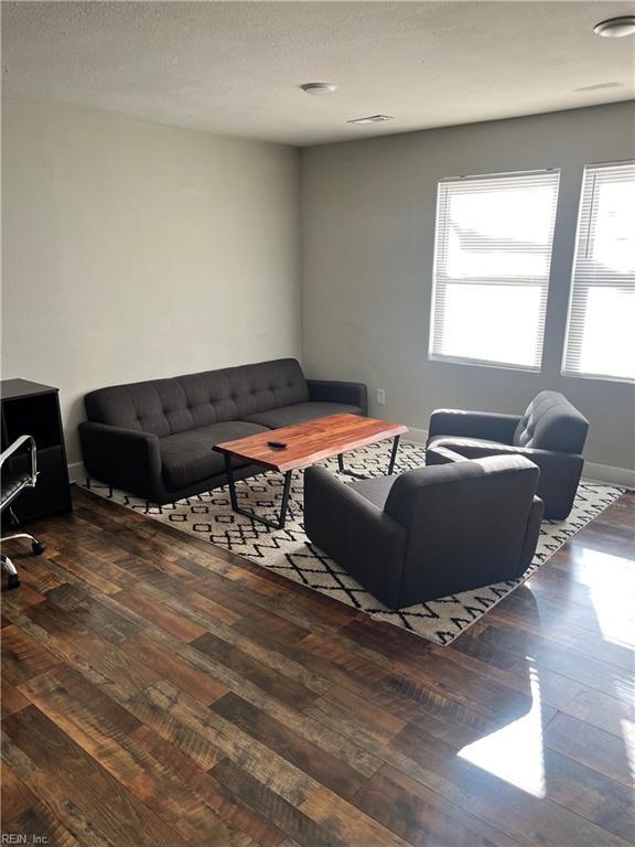 living room featuring dark wood-type flooring and a textured ceiling