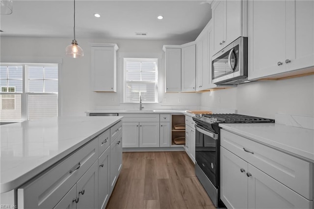 kitchen featuring sink, white cabinetry, appliances with stainless steel finishes, light stone countertops, and light hardwood / wood-style floors