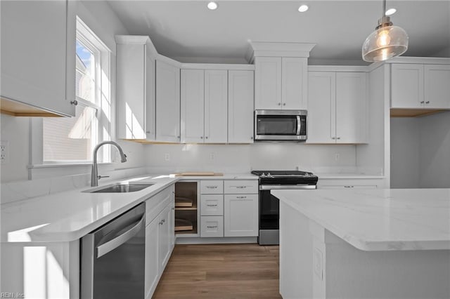 kitchen featuring pendant lighting, sink, appliances with stainless steel finishes, light stone countertops, and white cabinets