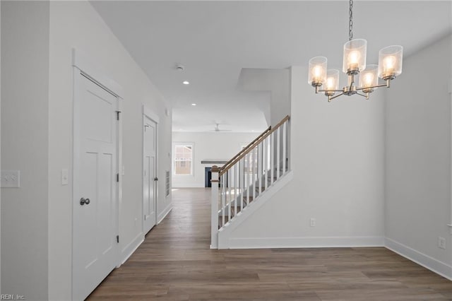 foyer with wood-type flooring and ceiling fan with notable chandelier