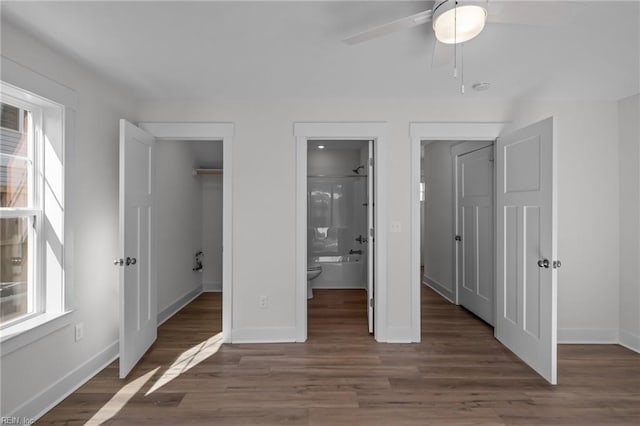 unfurnished bedroom with ensuite bathroom, dark hardwood / wood-style flooring, a spacious closet, ceiling fan, and a closet