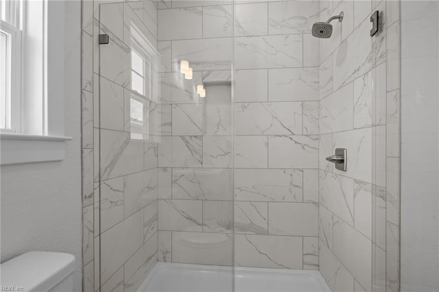 bathroom with a tile shower and toilet