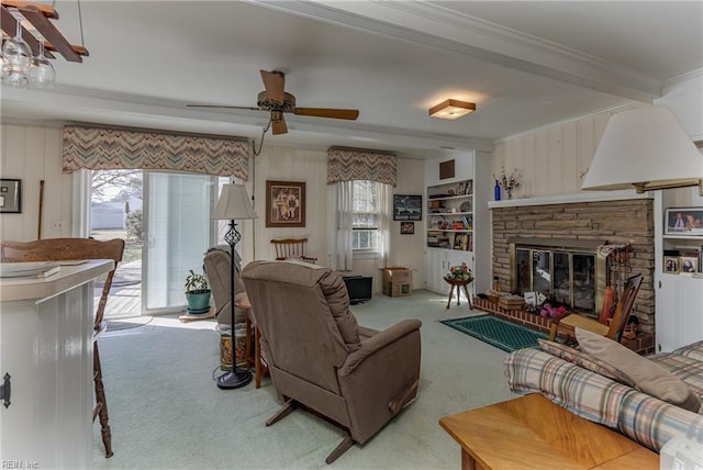 carpeted living room with ornamental molding, a stone fireplace, built in features, and ceiling fan