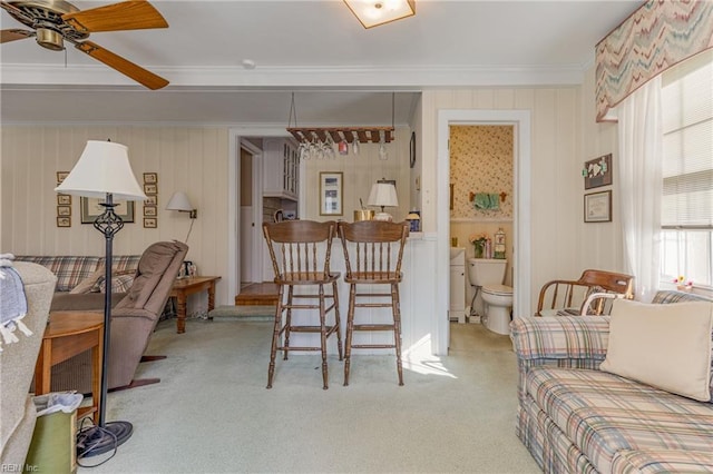 living room with ornamental molding, light colored carpet, and ceiling fan