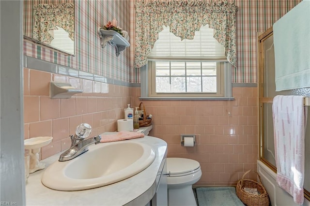 full bathroom featuring vanity, combined bath / shower with glass door, tile walls, and toilet