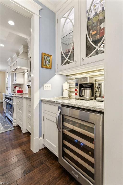 bar with white cabinets, beverage cooler, dark hardwood / wood-style flooring, high end stainless steel range, and crown molding