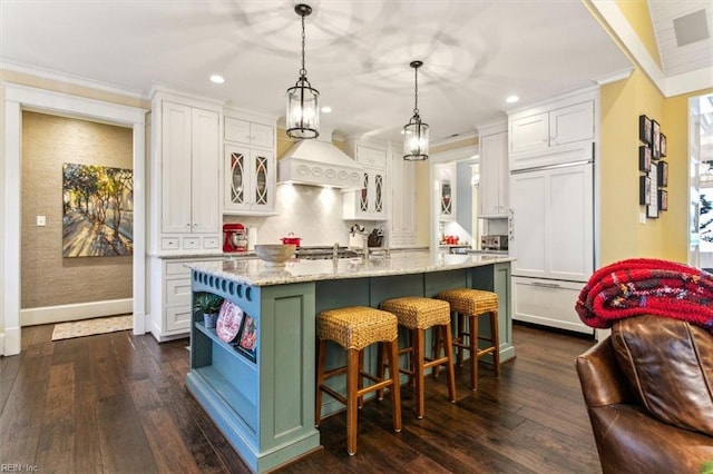 kitchen featuring white cabinetry, pendant lighting, an island with sink, and paneled built in refrigerator