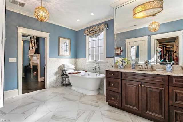 bathroom with ornamental molding, vanity, tile walls, and a washtub