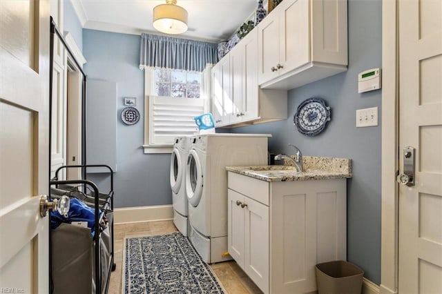 washroom with cabinets, washing machine and clothes dryer, crown molding, and sink