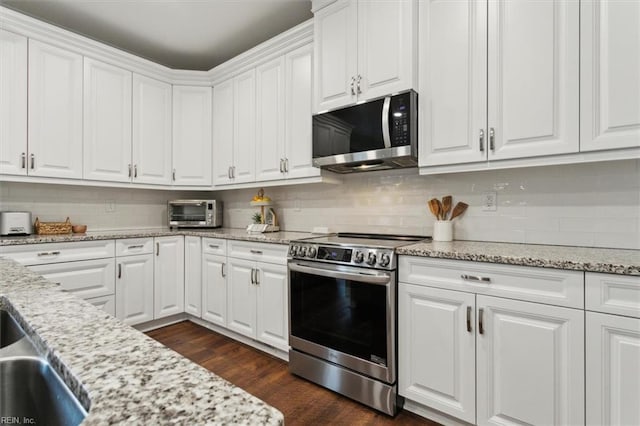 kitchen featuring appliances with stainless steel finishes, backsplash, white cabinets, and light stone counters