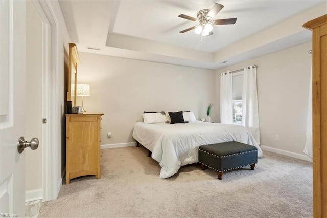 carpeted bedroom featuring ceiling fan and a tray ceiling