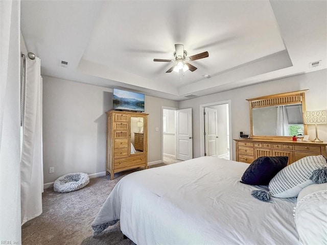 bedroom with a raised ceiling, carpet, and ceiling fan