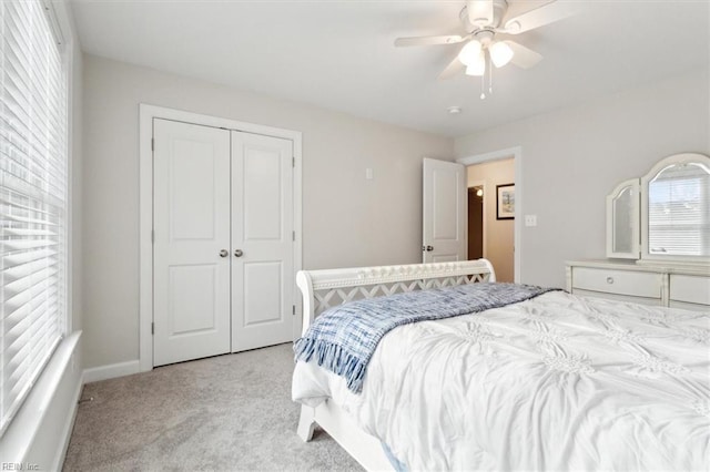 bedroom featuring light colored carpet, ceiling fan, and a closet