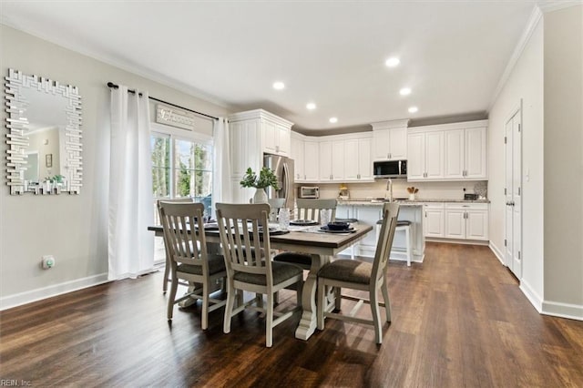 dining room featuring dark wood-type flooring, crown molding, and sink