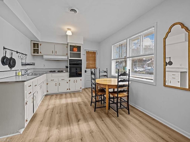 kitchen with sink, white cabinetry, white gas stovetop, light hardwood / wood-style floors, and oven