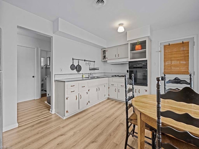 kitchen featuring sink, white cabinets, oven, light hardwood / wood-style floors, and gas stovetop