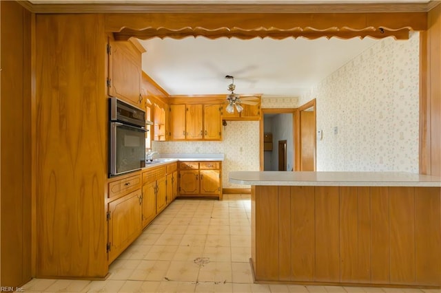 kitchen with sink, stainless steel oven, decorative light fixtures, kitchen peninsula, and ceiling fan