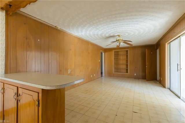 interior space with crown molding, wooden walls, built in features, and kitchen peninsula