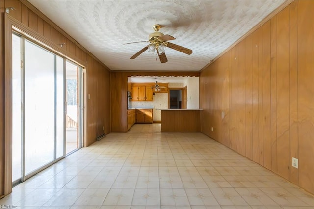 interior space with ceiling fan, ornamental molding, and wooden walls