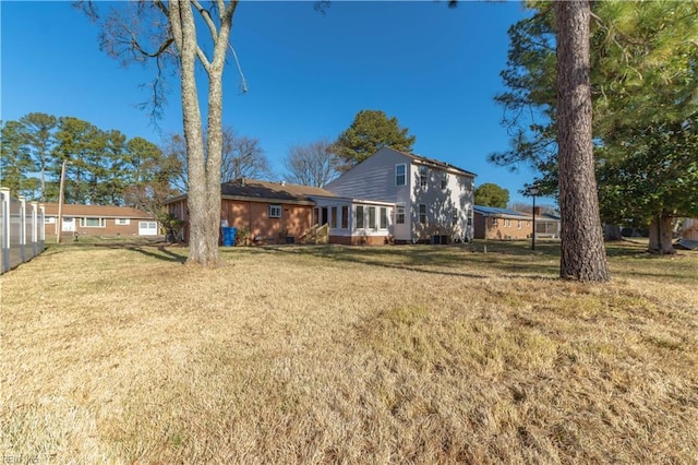 rear view of house featuring a sunroom and a lawn