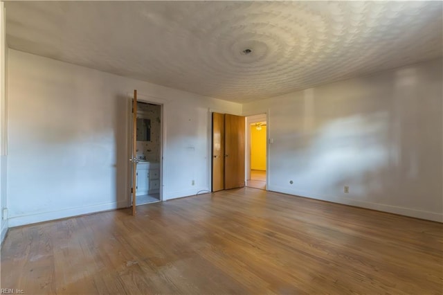 unfurnished bedroom featuring electric panel, a textured ceiling, and light wood-type flooring