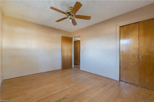 unfurnished bedroom featuring ceiling fan, a closet, and light wood-type flooring