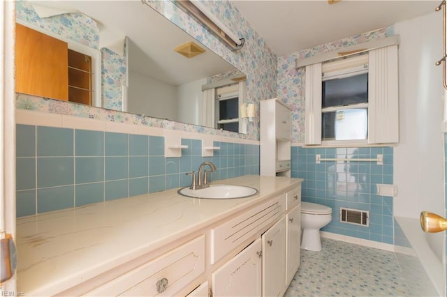 bathroom with a tub, tile walls, tile patterned flooring, vanity, and toilet