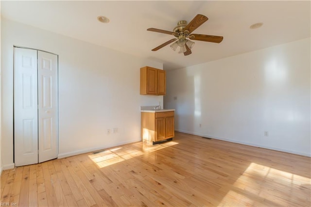 unfurnished living room featuring sink, ceiling fan, and light hardwood / wood-style flooring