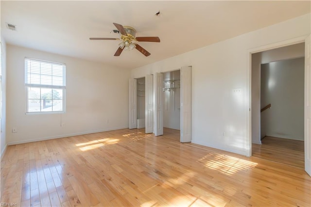 unfurnished bedroom with multiple closets, ceiling fan, and light wood-type flooring